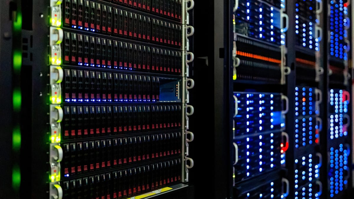 Baies de serveurs alignées, façades noires parsemées de voyants bleus, verts et rouges, dans une salle informatique