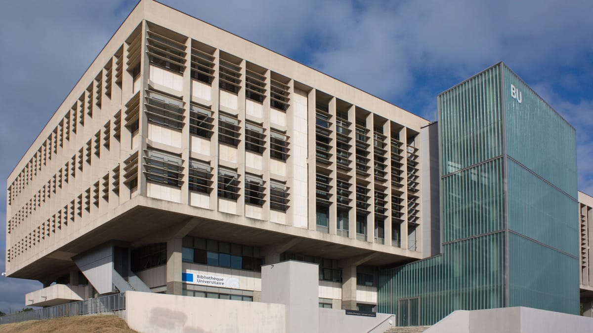 Façade en béton d'une bibliothèque universitaire à brise-soleil, flanquée d'une tour vitrée marquée BU