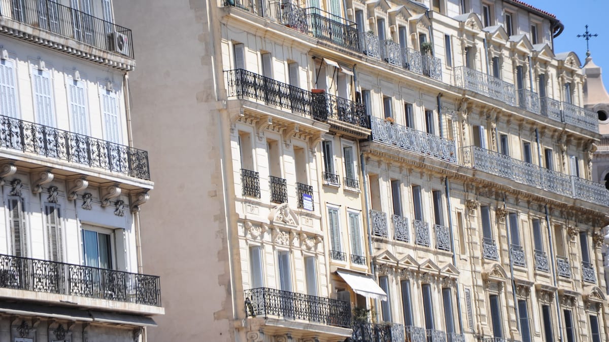 Façades d'immeubles d'habitation anciens à balcons en fer forgé, sous un ciel bleu
