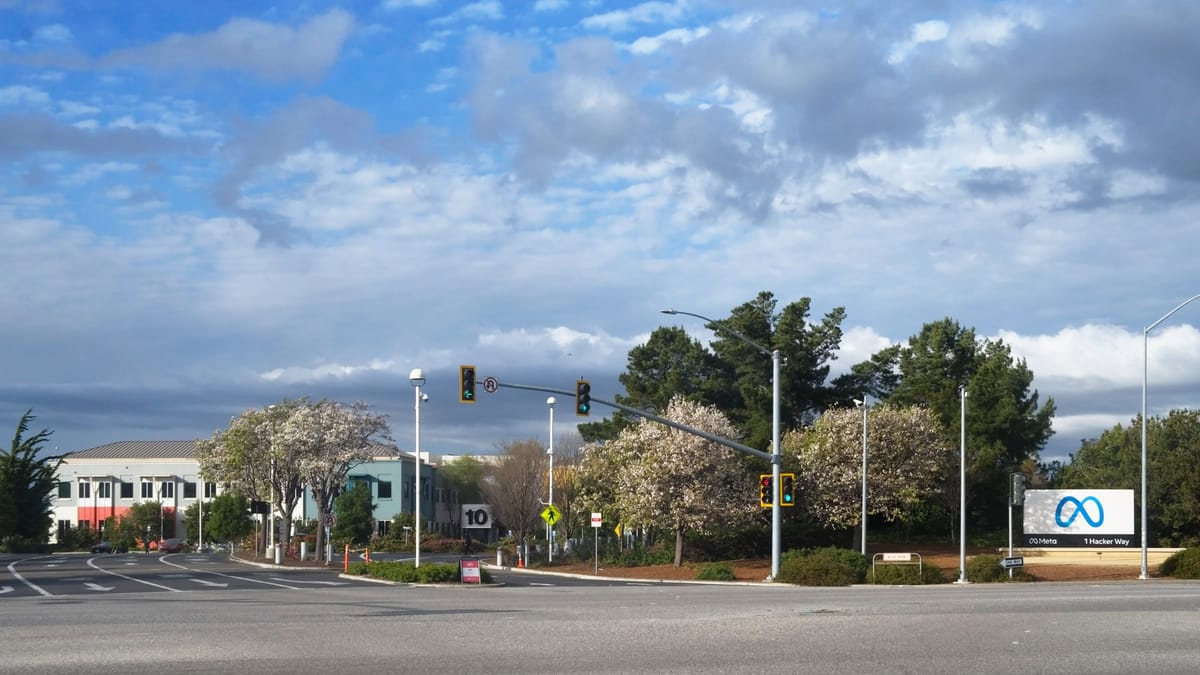 Carrefour devant l'entrée du siège de Meta à Menlo Park, en Californie, avec à droite le panneau au logo de l'entreprise