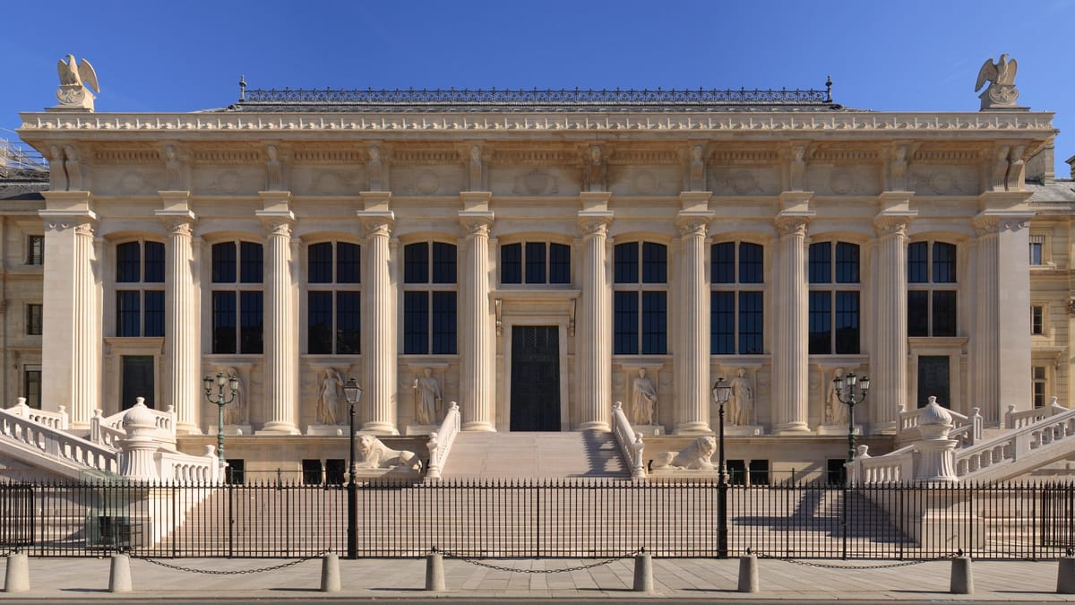 Façade néoclassique à colonnes d'un palais de justice, précédée d'un grand escalier et d'une grille